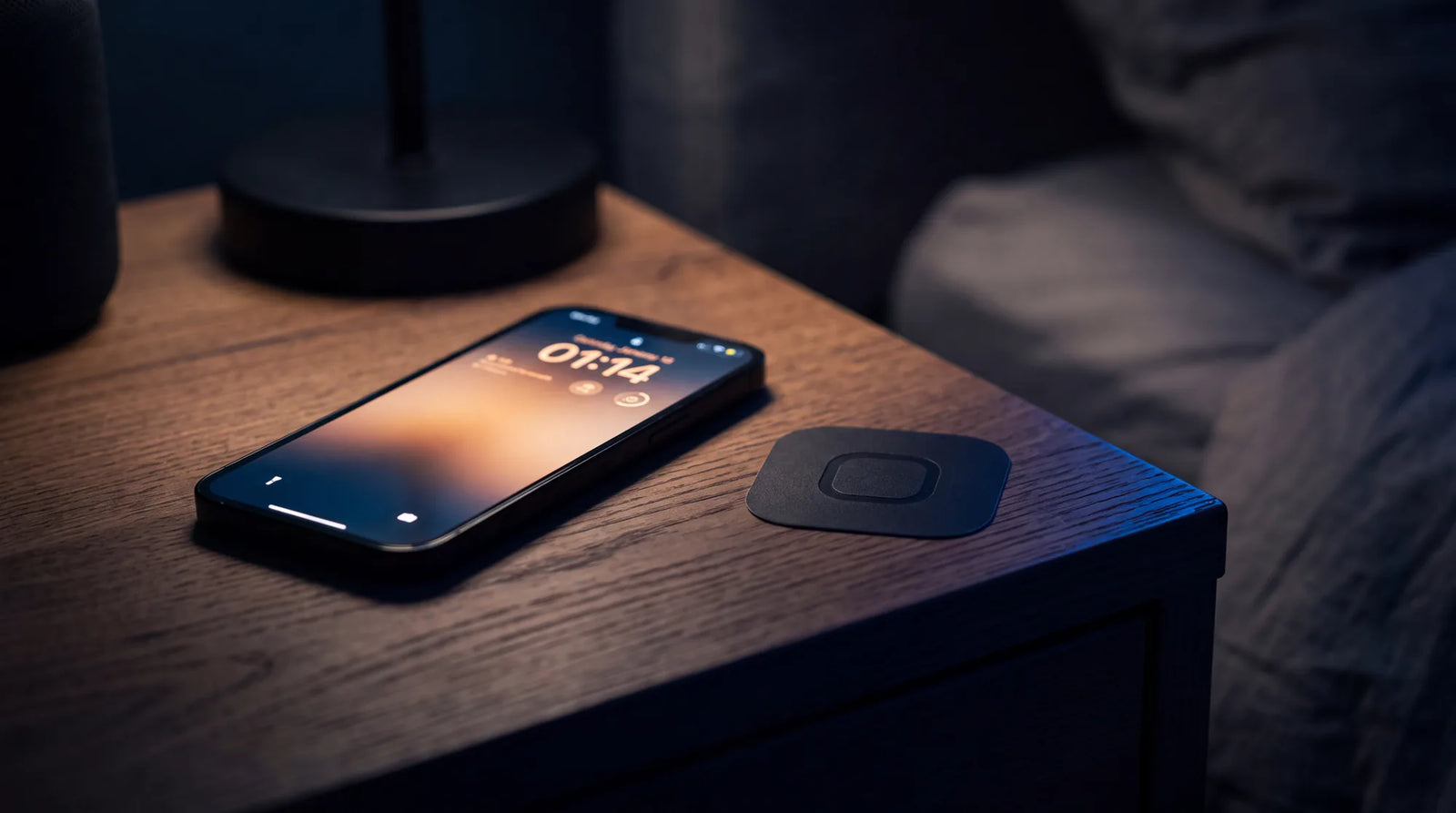 A phone glowing alone on a nightstand late at night, the KeyBlock sticker unlit beside it